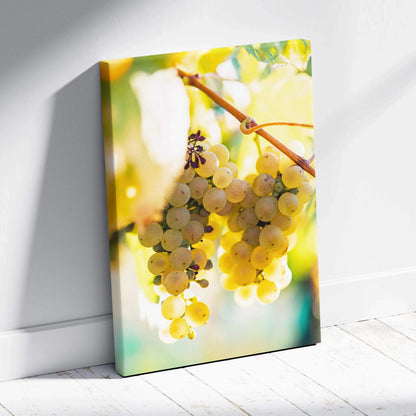 Vertical canvas wall art featuring vibrant yellow-green grape cluster with sunlight and soft-focus leaves in background,.