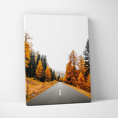 Vertical canvas wall art featuring a road through vibrant autumn trees with orange leaves.