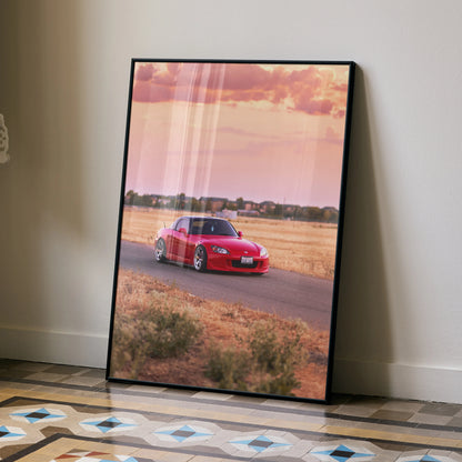Honda S2000 red sports car driving on rural road at sunset poster wall art with black frame.
