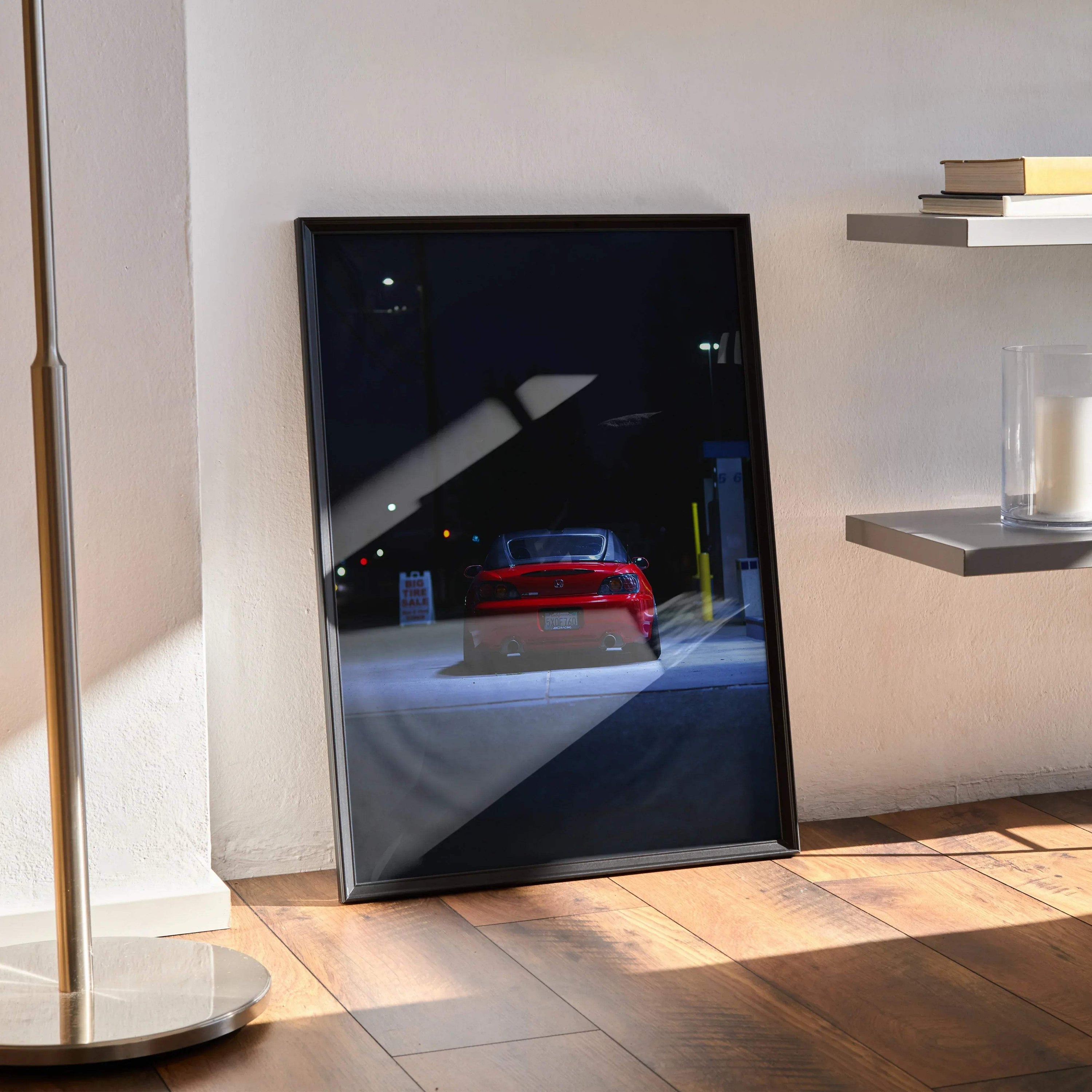 Honda S2000 red sports car poster leaning on floor, modern wall art with dark city background.