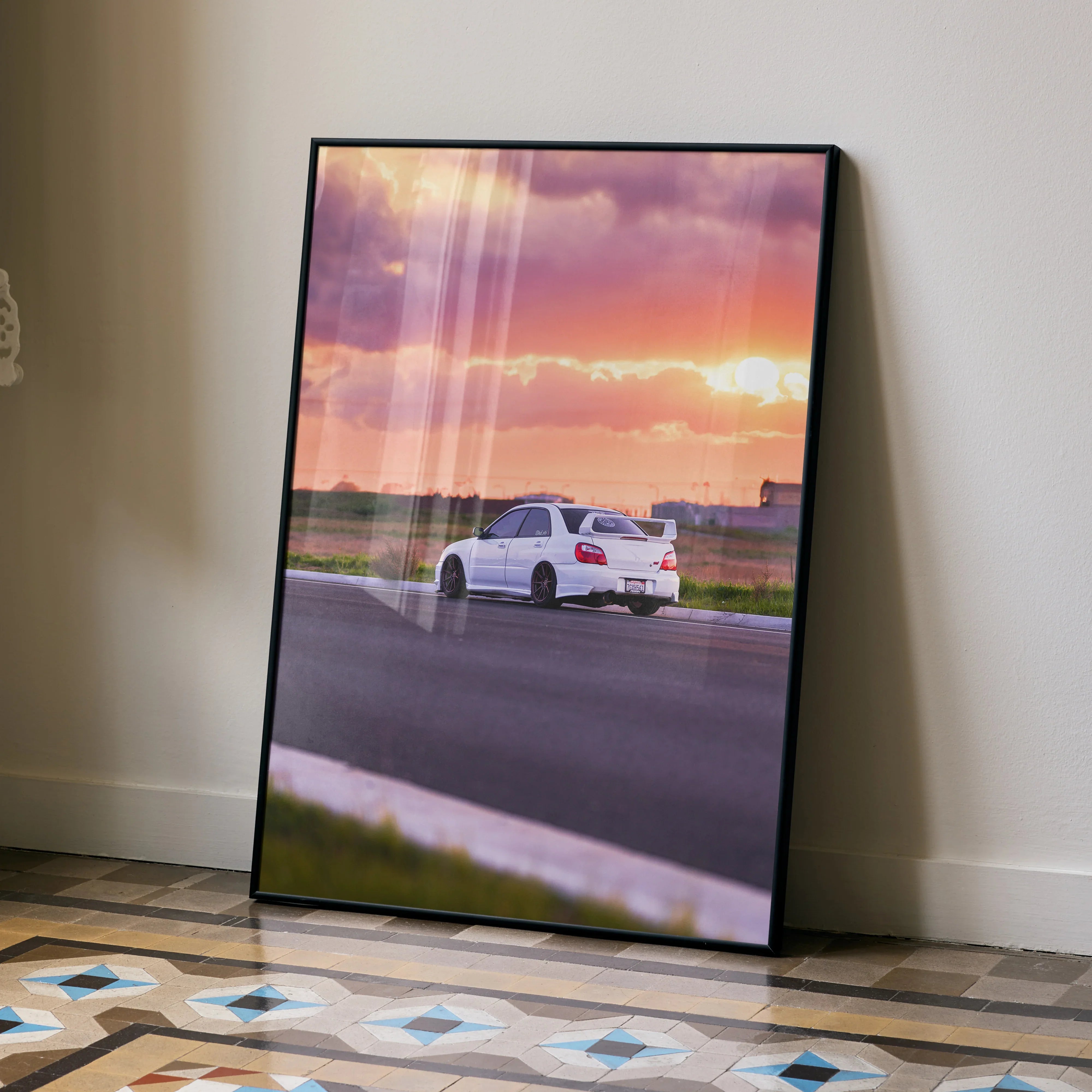 Subaru WRX STI driving on open road at sunset poster wall art with vibrant orange and purple sky.
