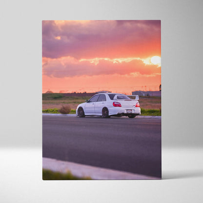 Vertical canvas wall art featuring a white Subaru WRX STI against a vibrant sunset sky.