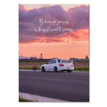 Motivational poster wall art with white Subaru WRX STI under purple and orange sunset sky and "Believe in yourself is the.