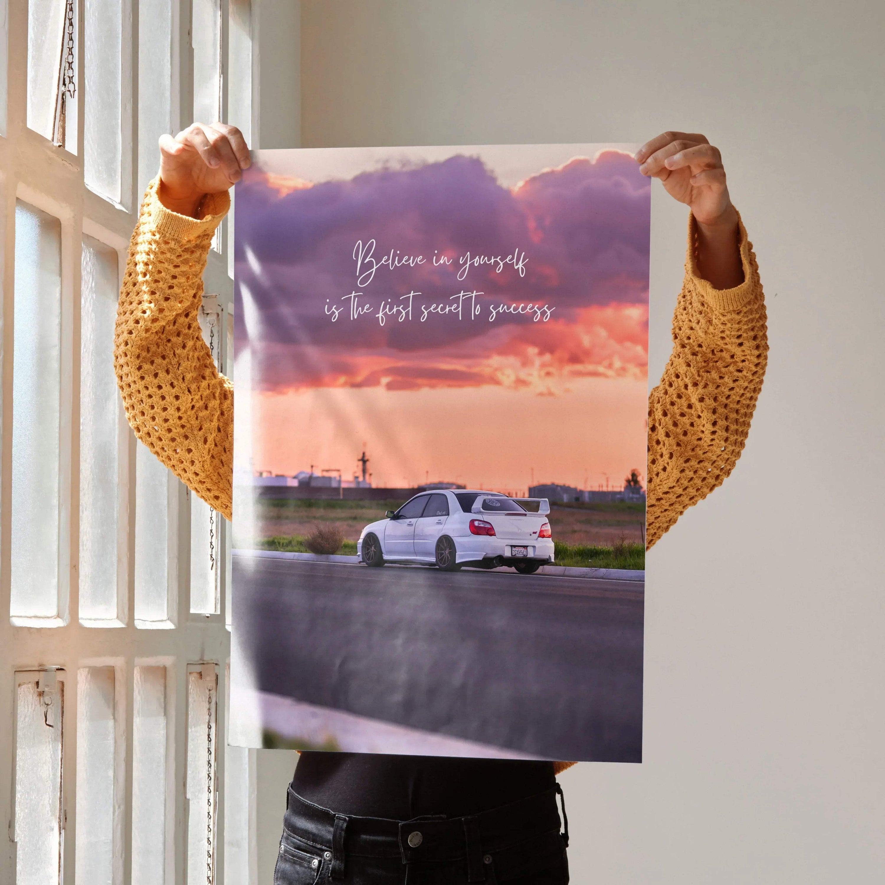 Motivational poster wall art of white Subaru WRX STI with inspiring text against a colorful sunset sky.