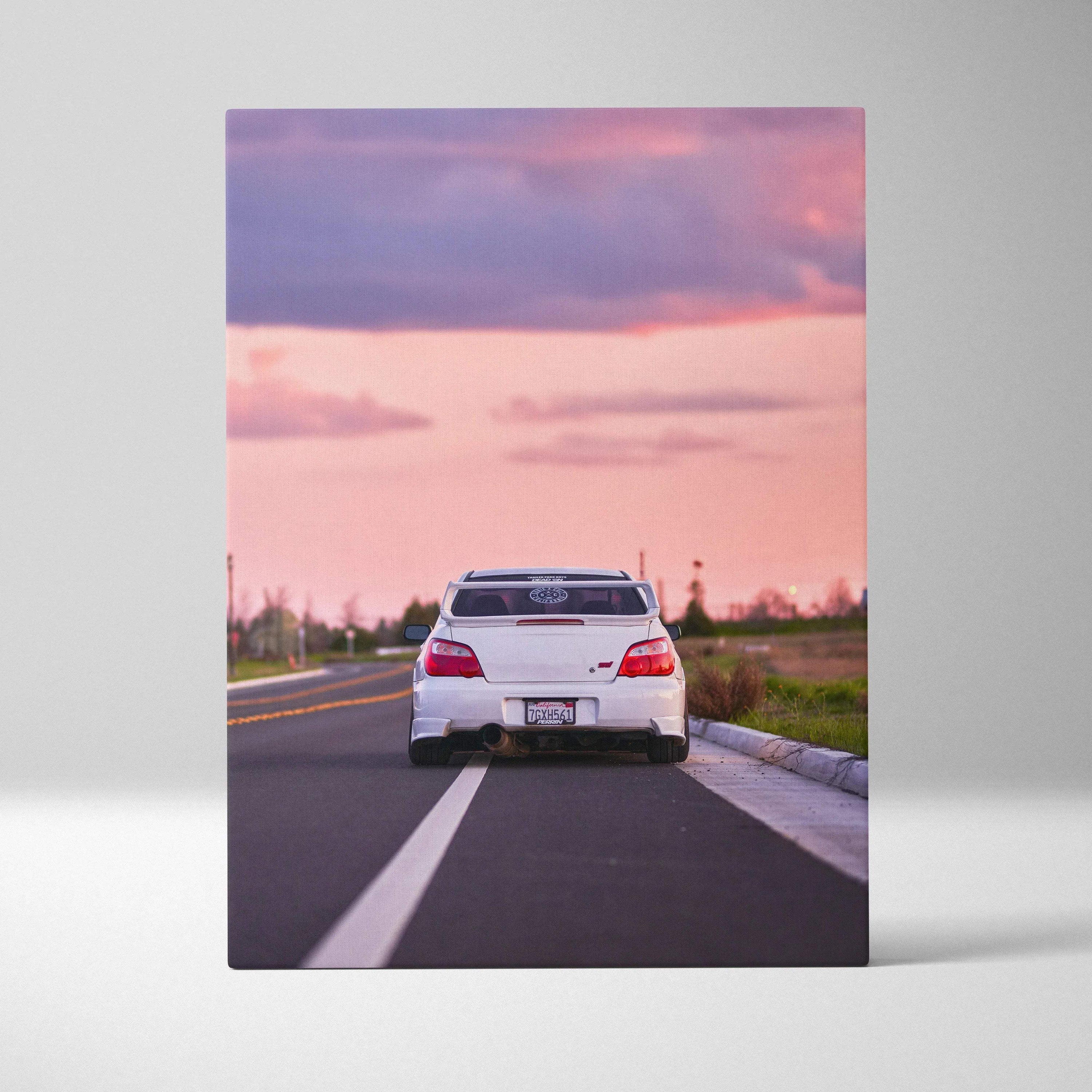 Vertical canvas wall art of white Subaru WRX STI on road at sunset with pink sky background.