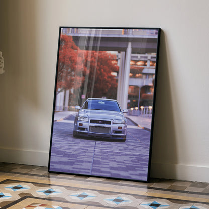 Nissan GTR R34 Skyline poster wall art with autumn cityscape background in black frame.