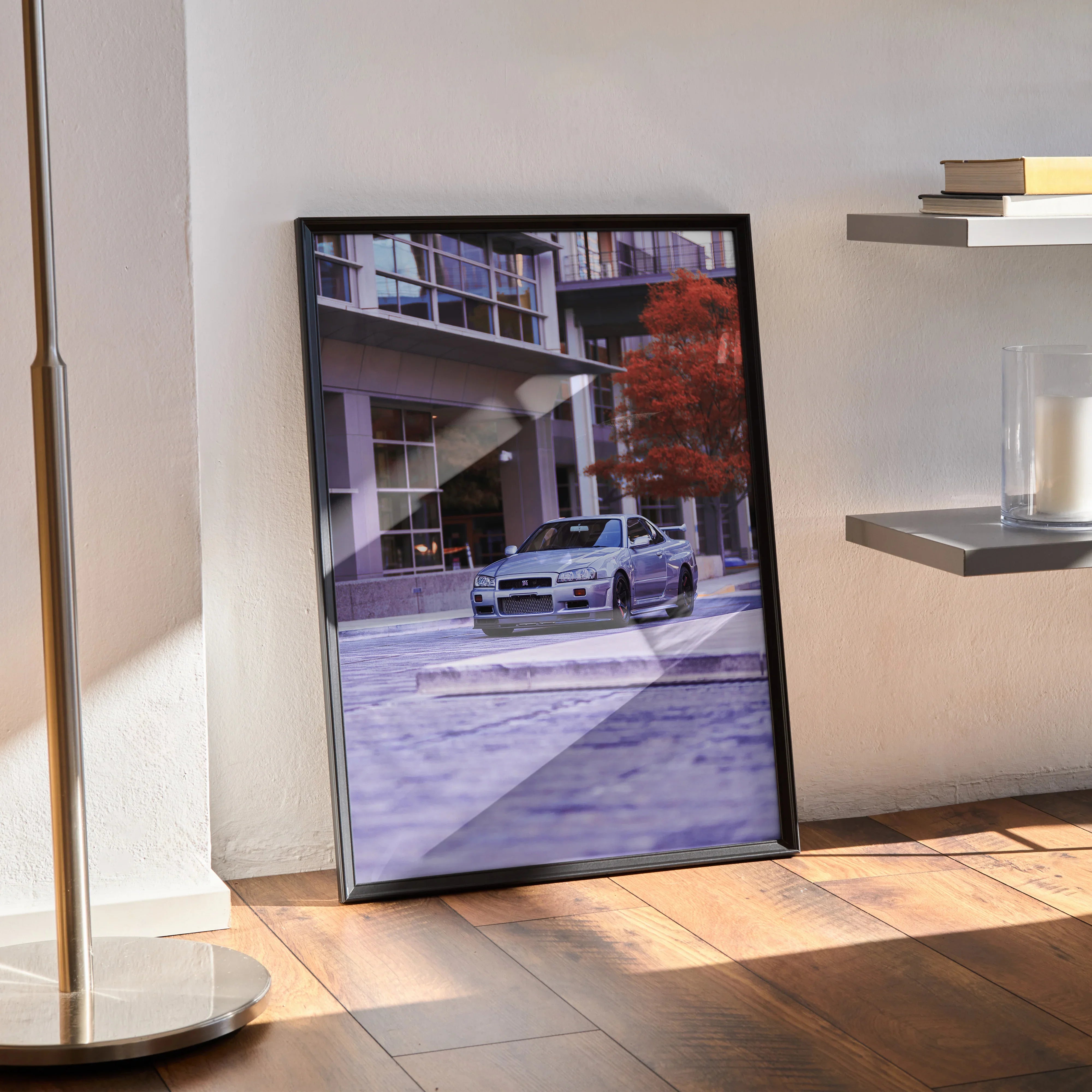 Nissan GTR R34 Skyline poster with urban background in black frame wall art resting on wooden floor.