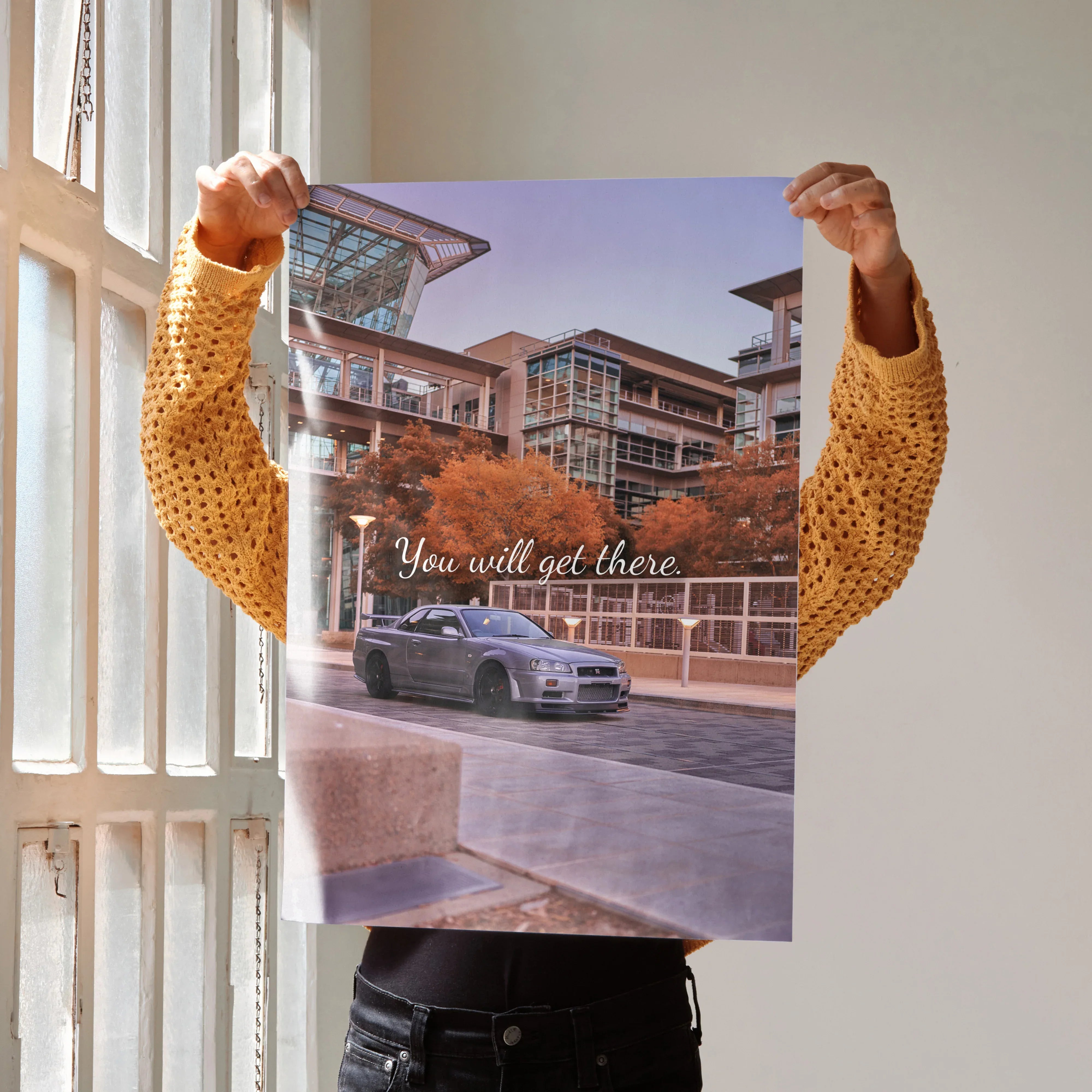 Motivational poster wall art featuring silver Nissan GT-R R34 Skyline parked by modern urban buildings with "You will get.