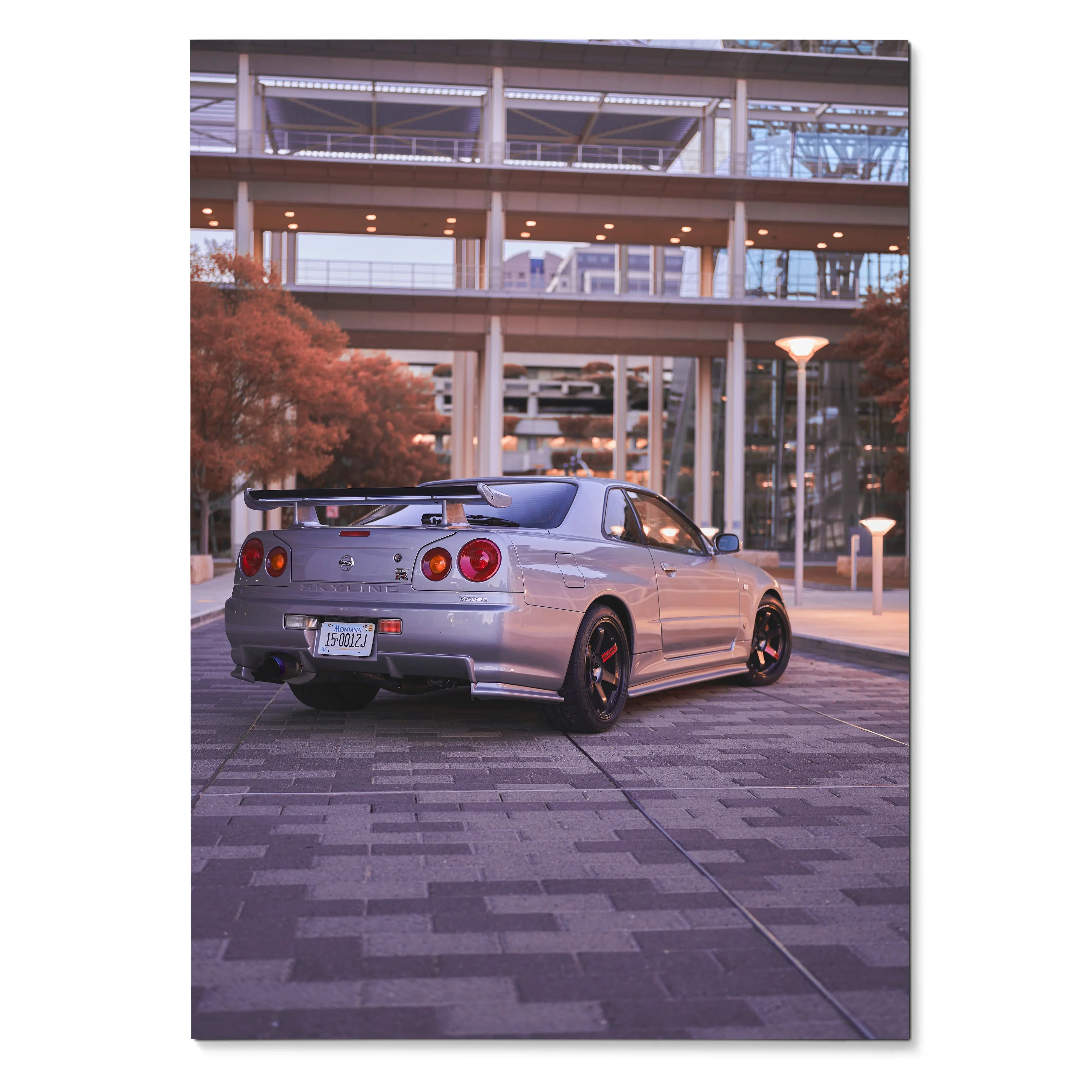 Nissan R34 GTR Skyline poster showing rear view with urban backdrop, sleek silver car, and modern architecture wall art.