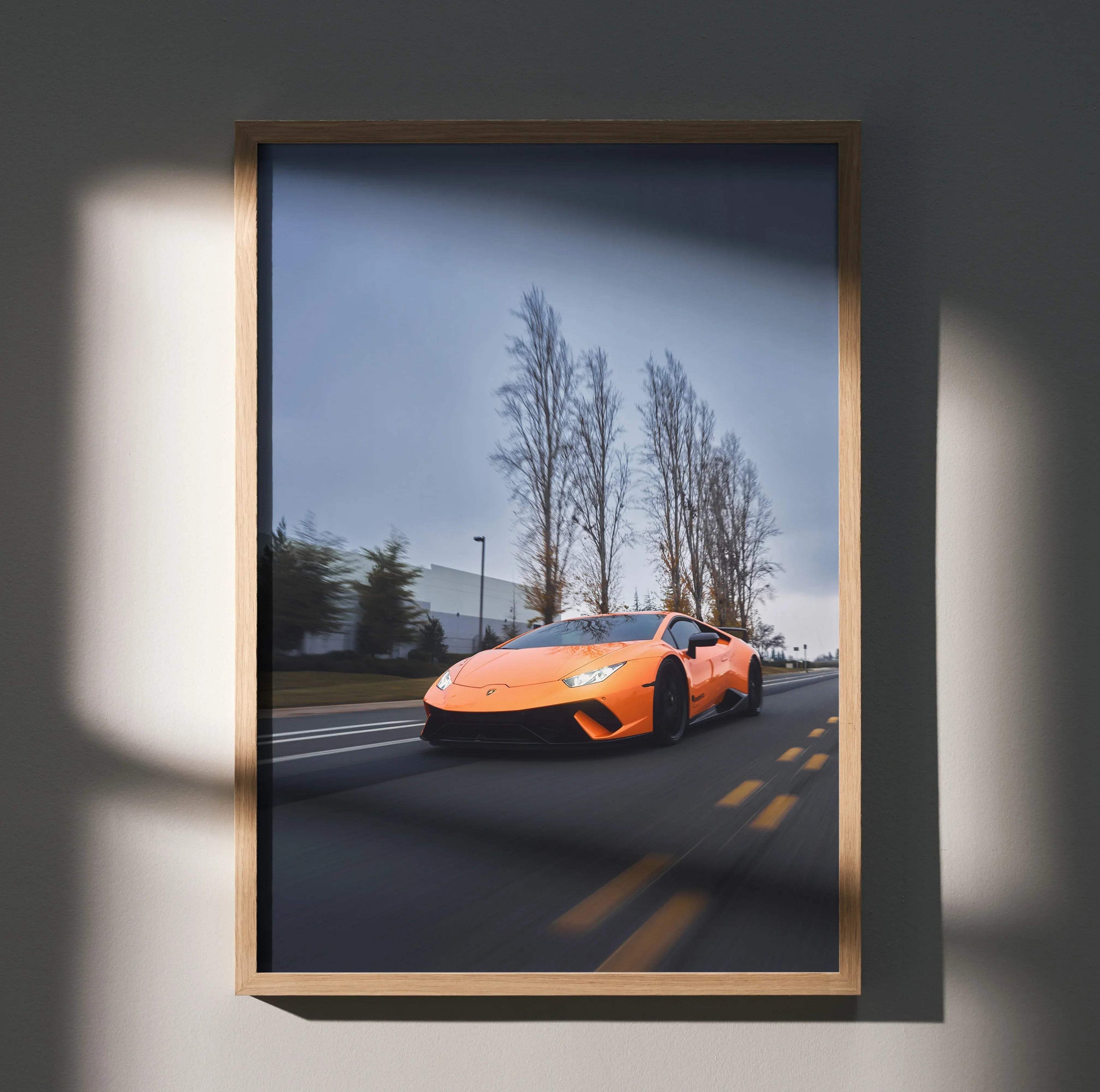 Orange Lamborghini Huracan driving on road with bare trees, premium wall art poster in wooden frame.