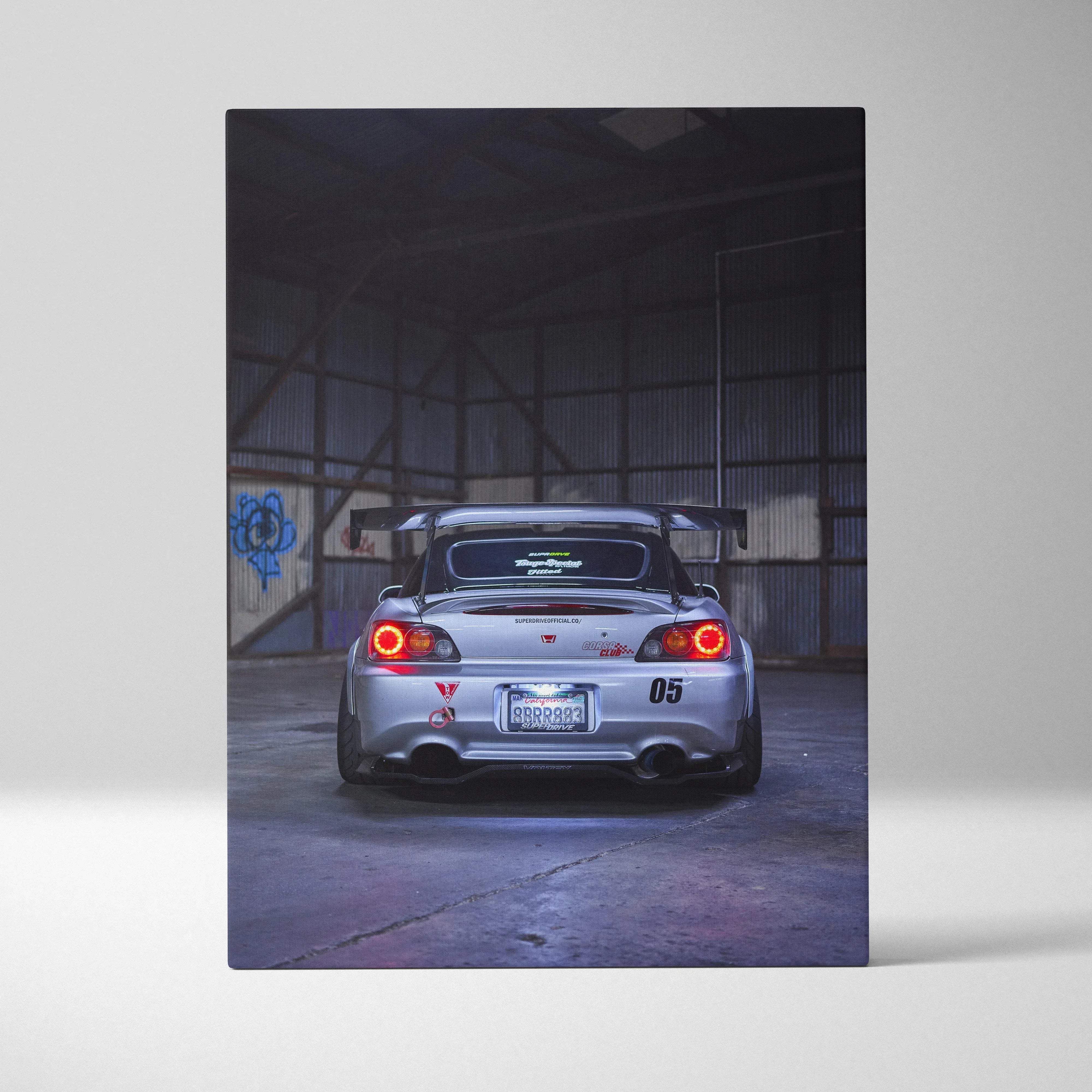 Canvas wall art featuring a high resolution vertical print of a silver Honda S2000 with rear spoiler and red taillights in an industrial garage