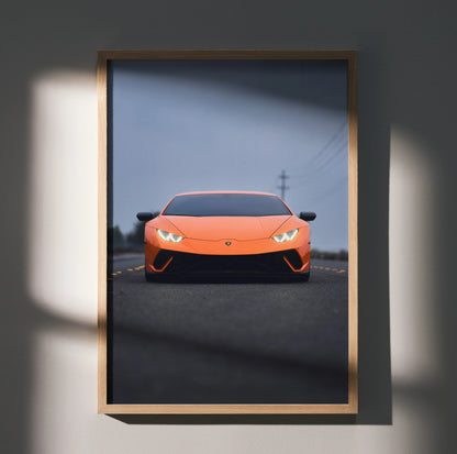 Orange Lamborghini Huracan poster with sleek front view on dark road, framed wall art with shadow detail.