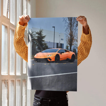 Orange Lamborghini Huracan poster showcasing sleek sports car in urban setting, glossy wall art.