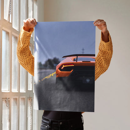 Poster wall art featuring rear view of orange Lamborghini Huracan speeding on track at sunset.