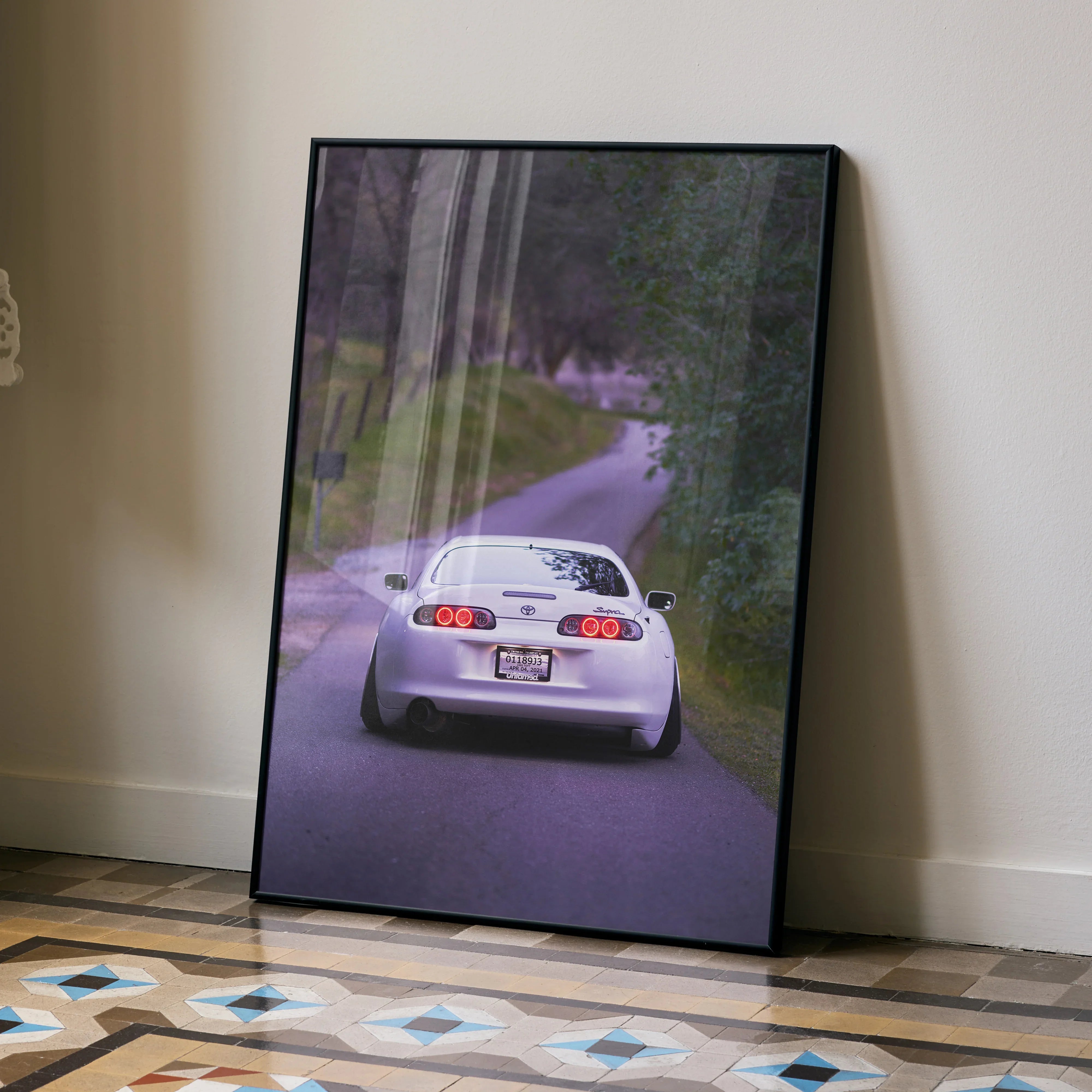 Toyota Supra MK4 driving on winding road poster wall art in black frame.
