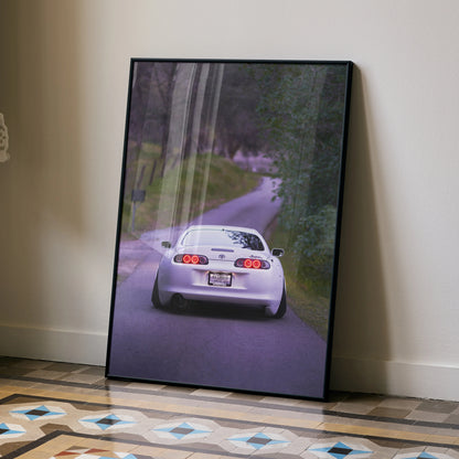 Toyota Supra MK4 driving on winding road poster wall art in black frame.