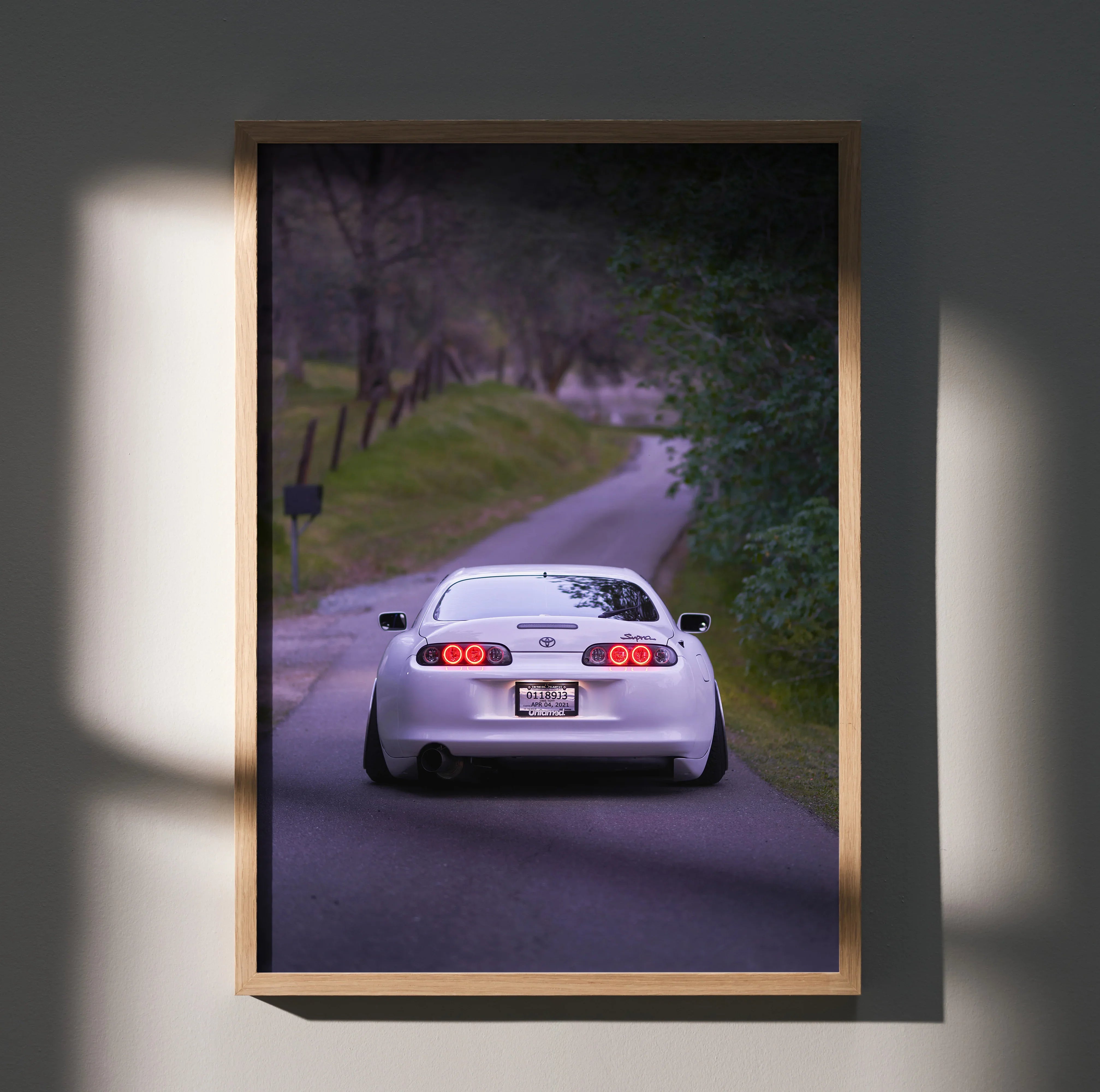 Toyota Supra MK4 poster wall art showing rear view of white sports car on winding road.