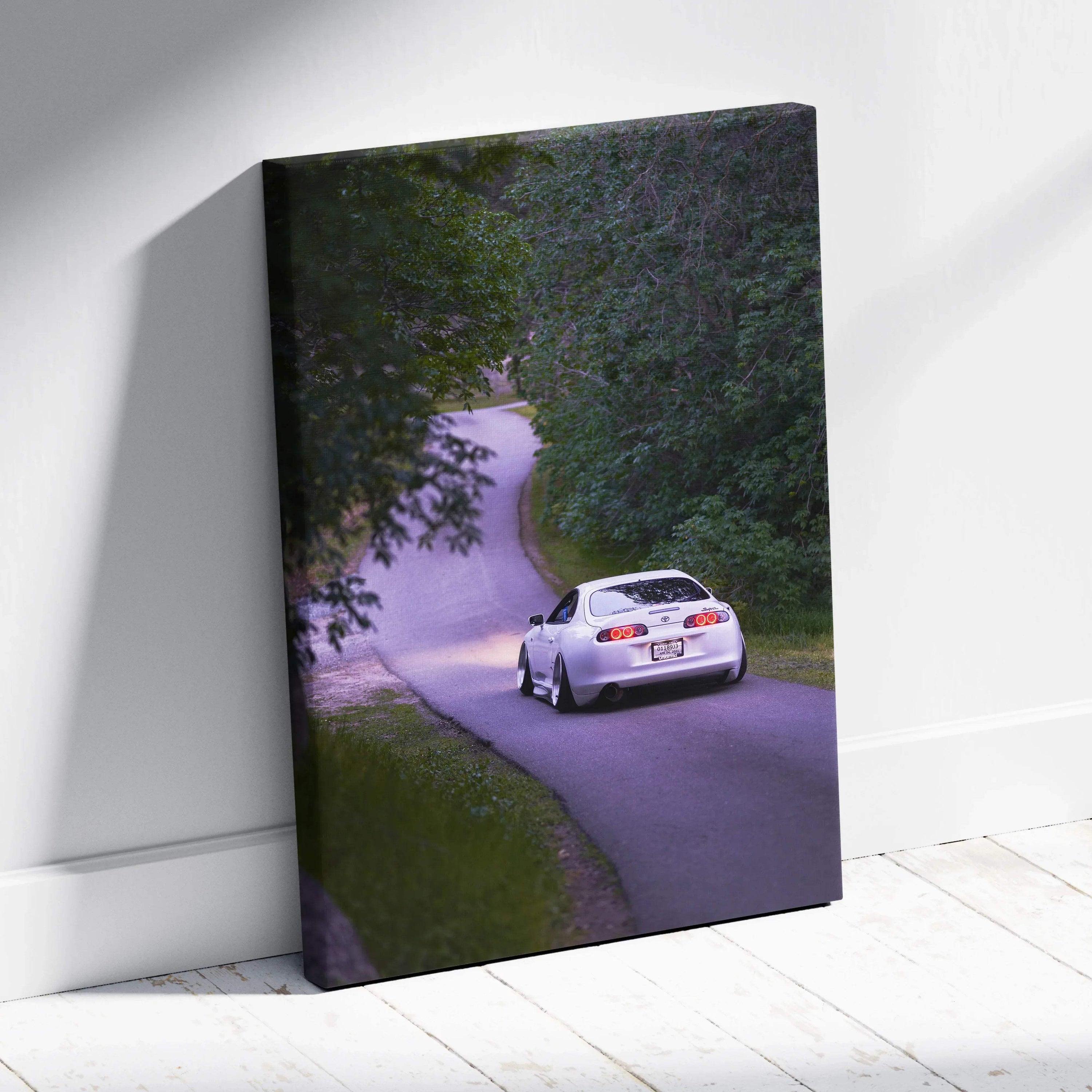 Toyota Supra MK4 driving on winding road canvas wall art with lush green trees.