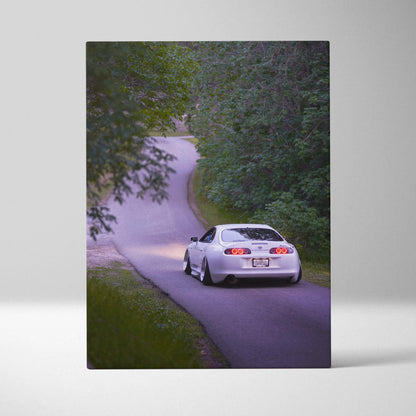 White Toyota Supra MK4 driving on winding forest road vertical canvas wall art.
