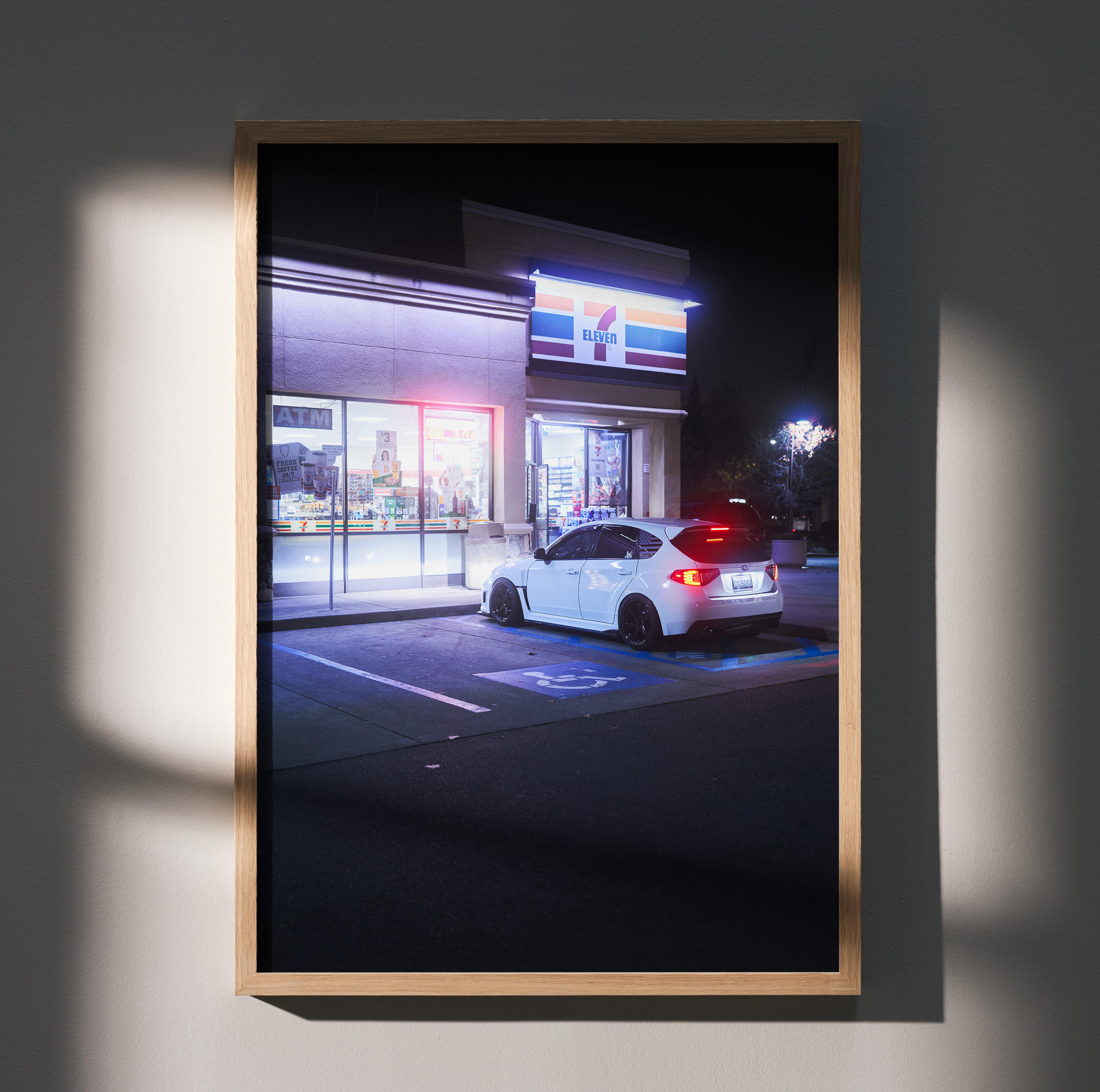 Subaru WRX STI parked at night outside a 7-Eleven, vibrant poster wall art in wooden frame.