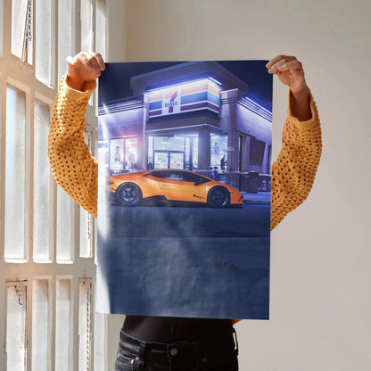 Lamborghini Huracan poster wall art featuring orange sports car in front of modern lit building at night.