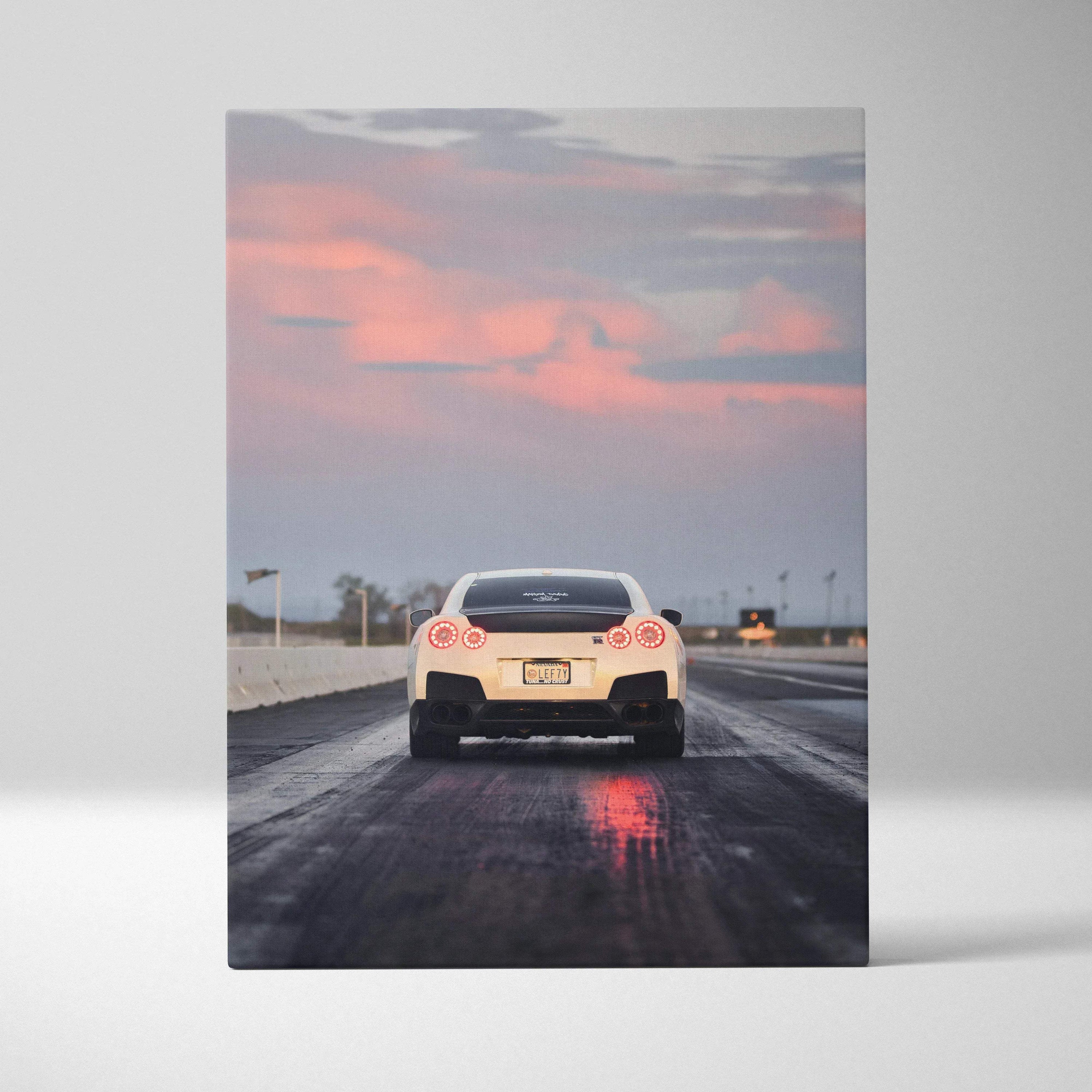 Nissan R35 GTR rear view on road at sunset canvas wall art with pink sky reflection.