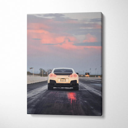 Vertical canvas wall art featuring rear view of white Nissan R35 GTR on wet road at sunset.