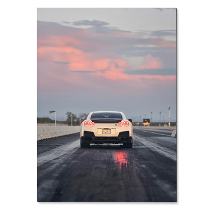 Nissan GTR R35 rear view on wet road at sunset poster wall art with pink sky clouds.