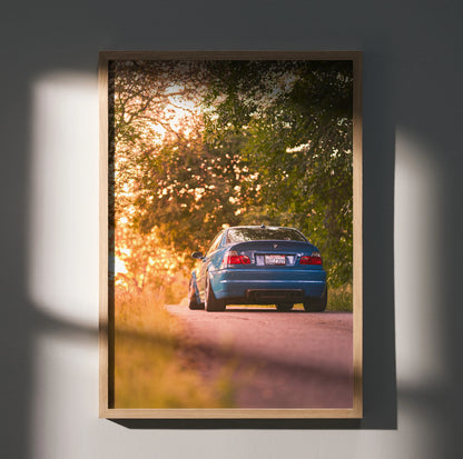 BMW E46 M3 sunset rear view poster wall art with vibrant natural lighting and trees.