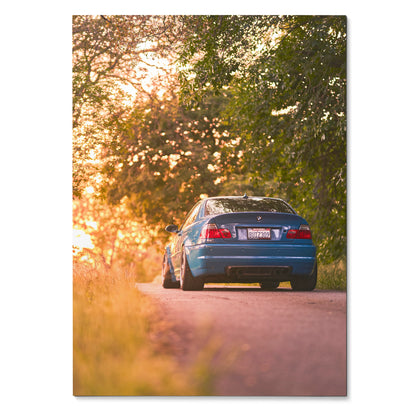 BMW E46 M3 poster showing rear view of blue car on sunset-lit road with trees, wall art decor.