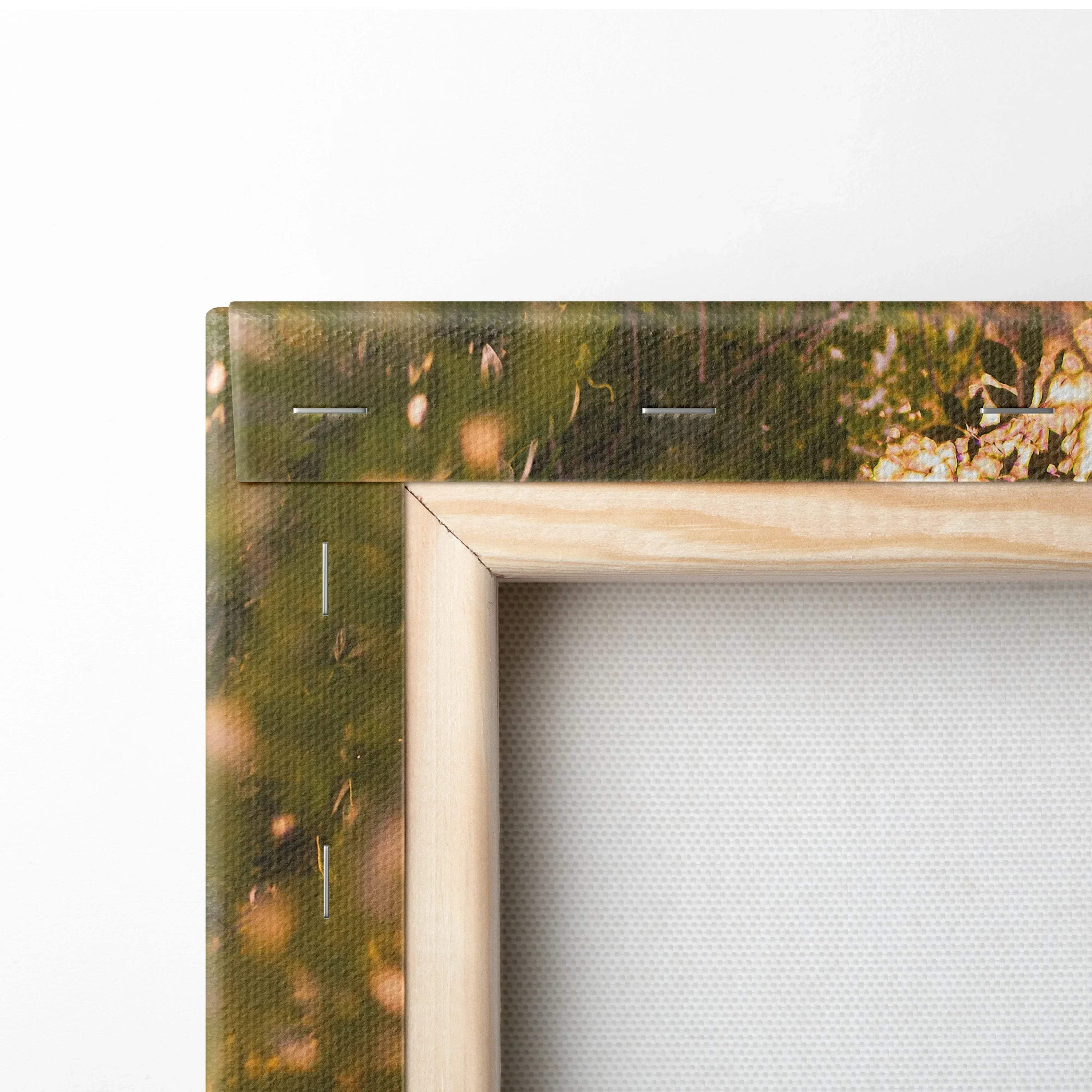 Close-up of wooden frame corner on canvas wall art with textured white canvas and blurred nature background.