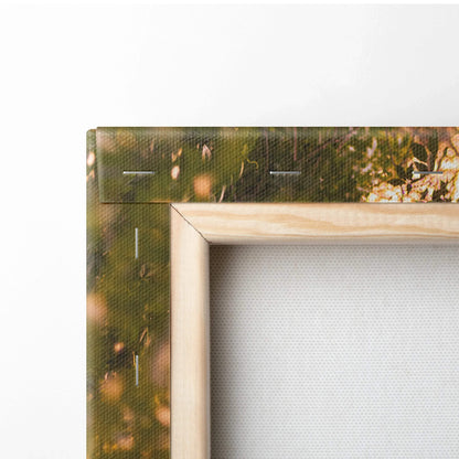 Close-up of wooden frame corner on canvas wall art with textured white canvas and blurred nature background.