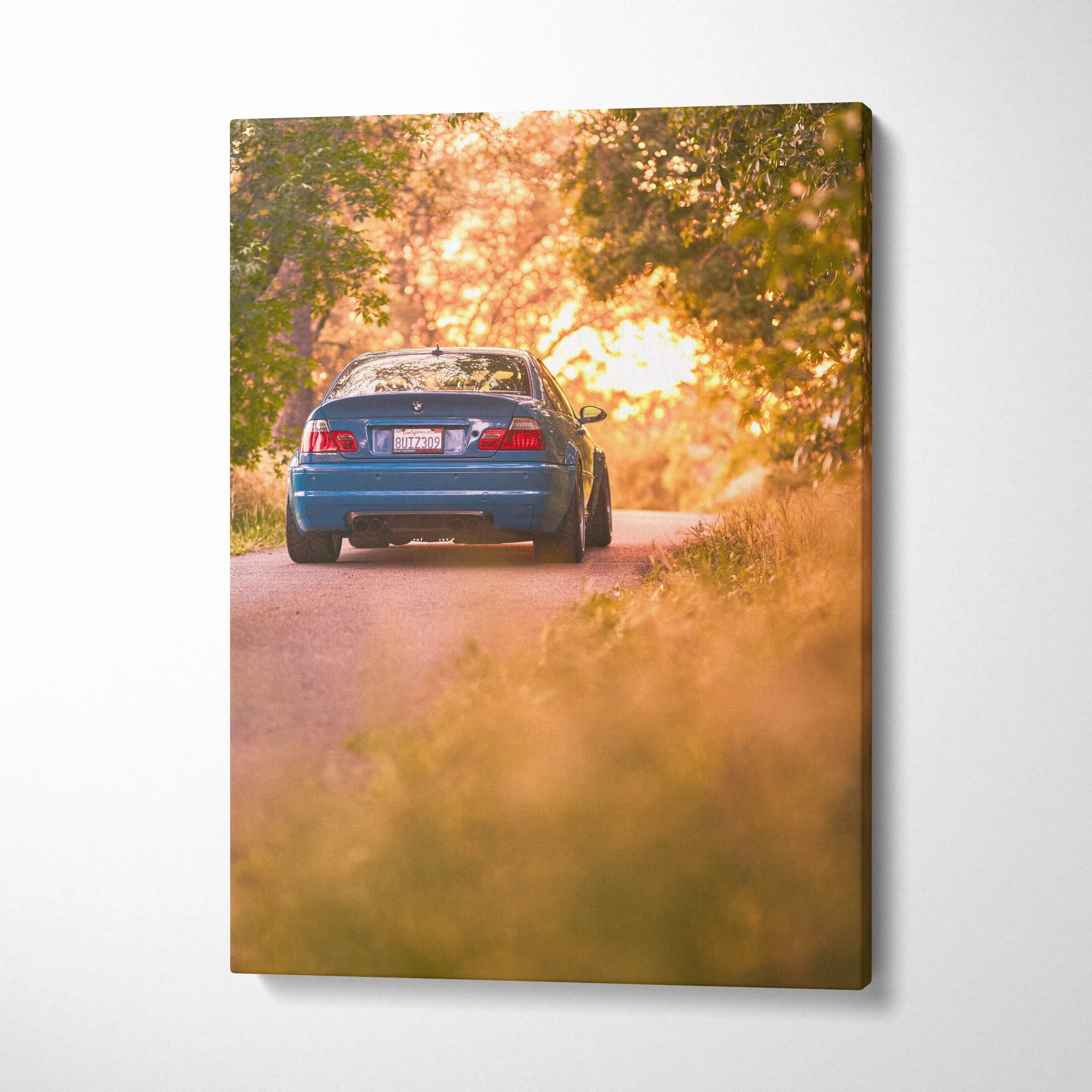 BMW E46 M3 on a sunlit tree-lined road canvas wall art with warm sunset tones.