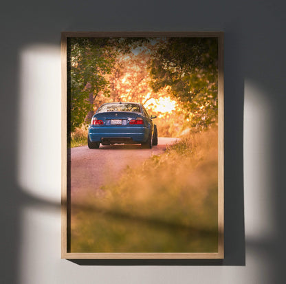 BMW E46 M3 poster featuring rear view of blue car on sunset-lit road, automotive wall art.