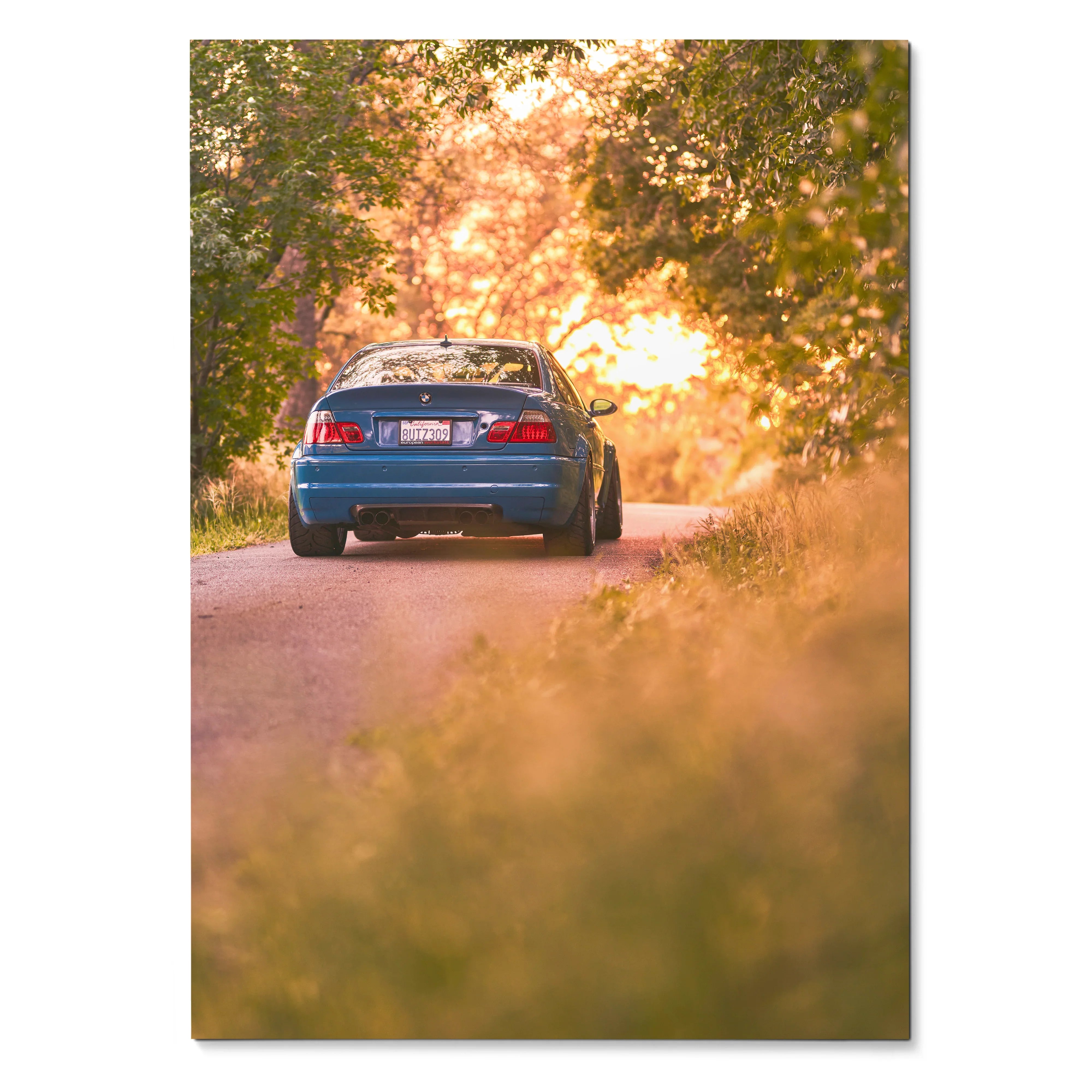 BMW E46 M3 parked on sunlit tree-lined road at sunset poster wall art.