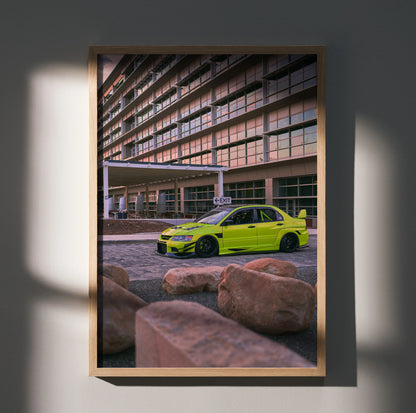 Mitsubishi Evo 9 in bright yellow parked by modern building poster wall art in wooden frame.