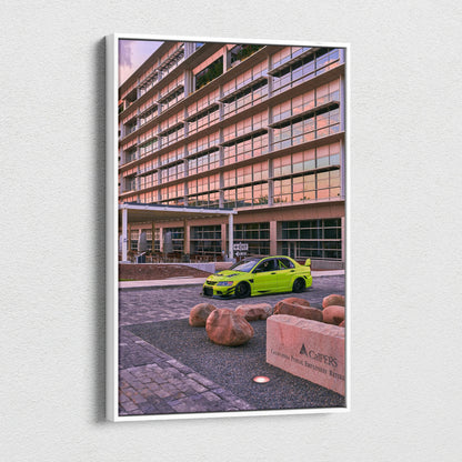 Vertical canvas wall art featuring a bright green Mitsubishi Evo 9 parked by a modern building at sunset.