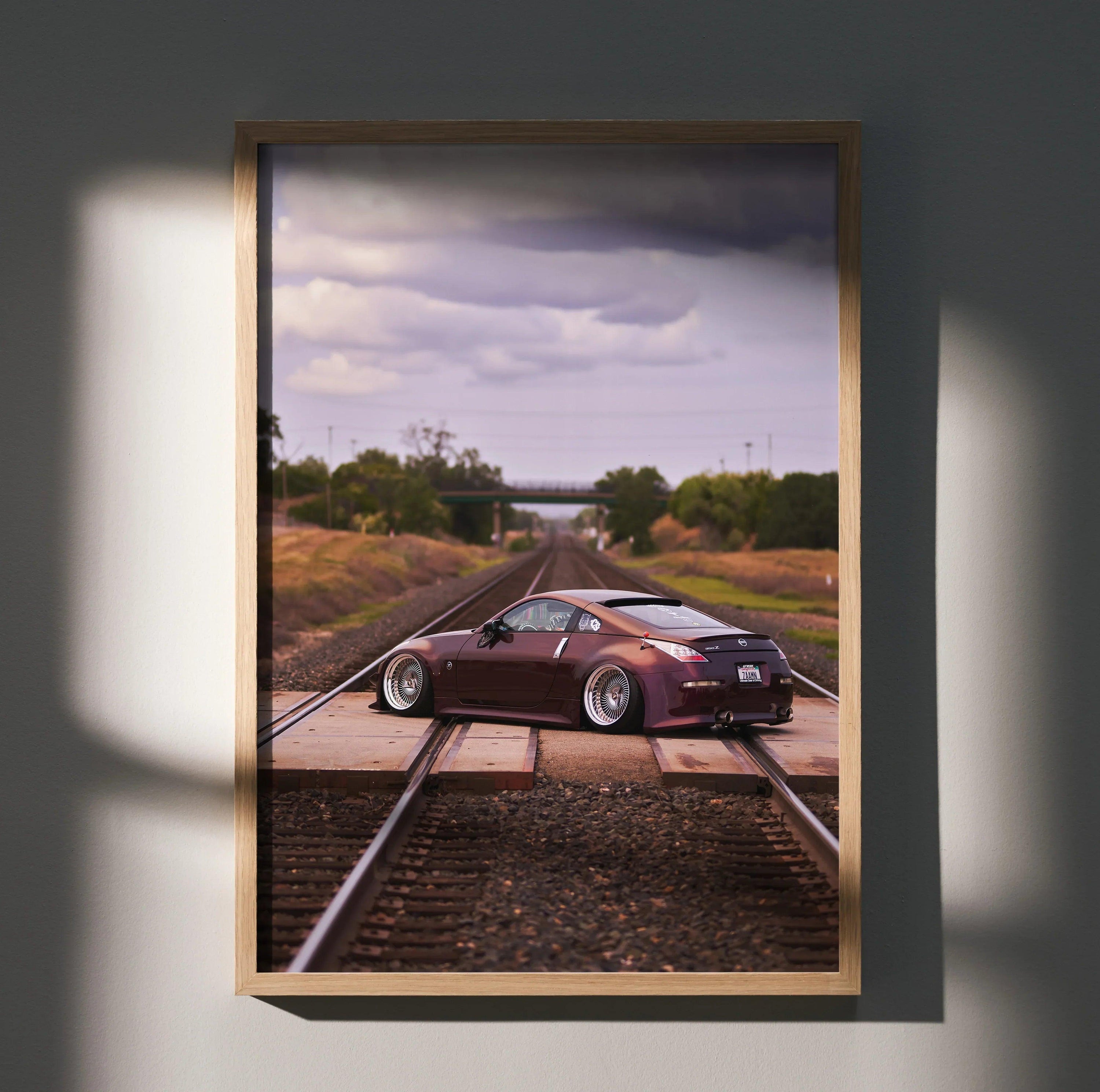 Nissan 350Z poster with sleek car on railroad tracks under cloudy sky, automotive wall art.