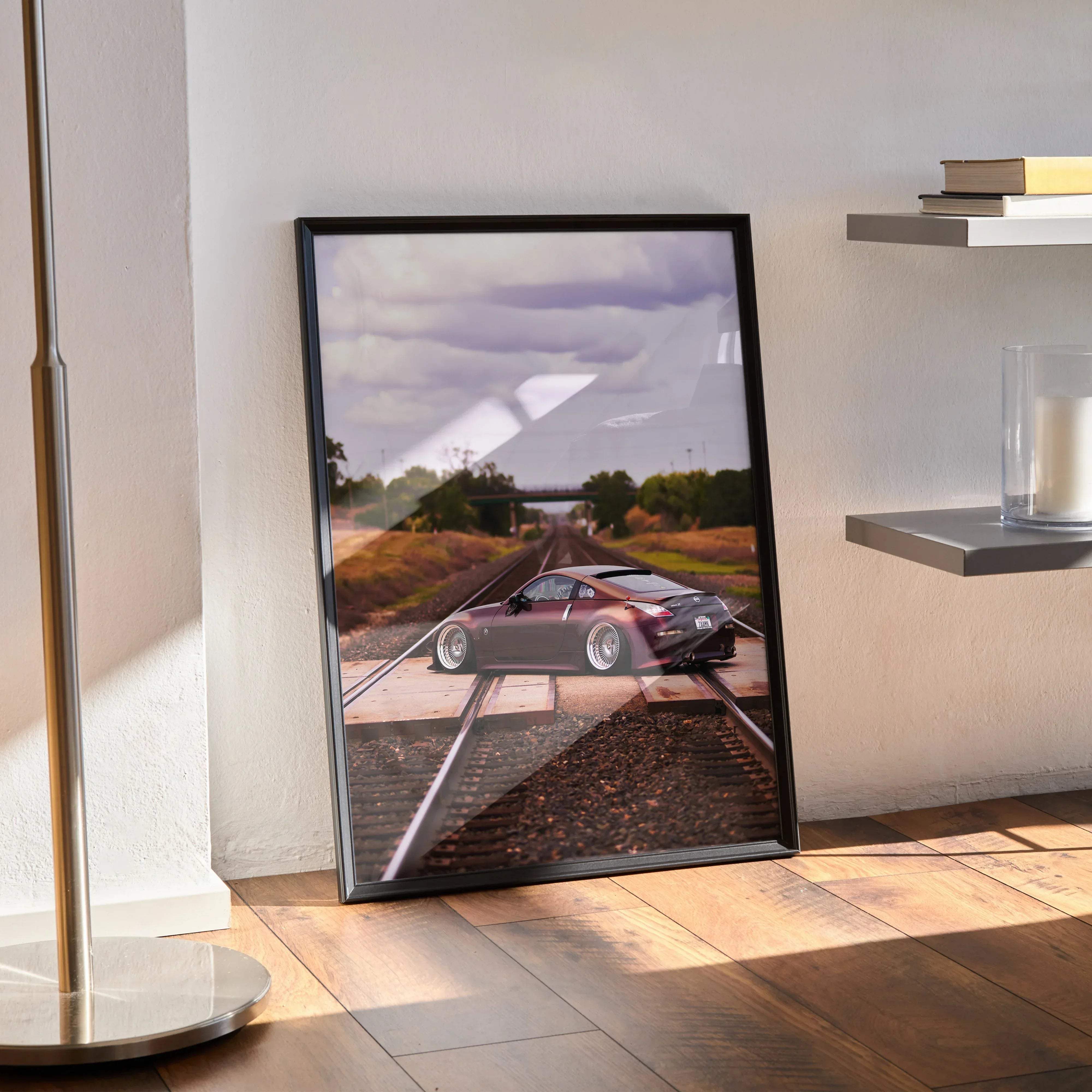 Black-framed nissan 350z automotive art poster featuring a maroon sports car on train tracks under cloudy sky