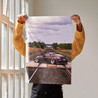 Poster of a maroon Nissan 350Z on railroad tracks at sunset, automotive wall art.