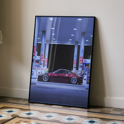 Nissan 350Z red sports car poster leaning against wall, high-resolution wall art at gas station.
