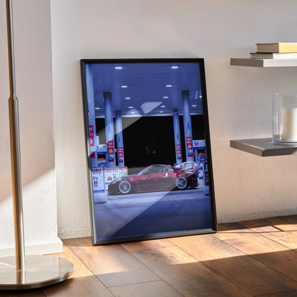 Nissan 350Z poster wall art with sleek red sports car parked at modern gas station at night.