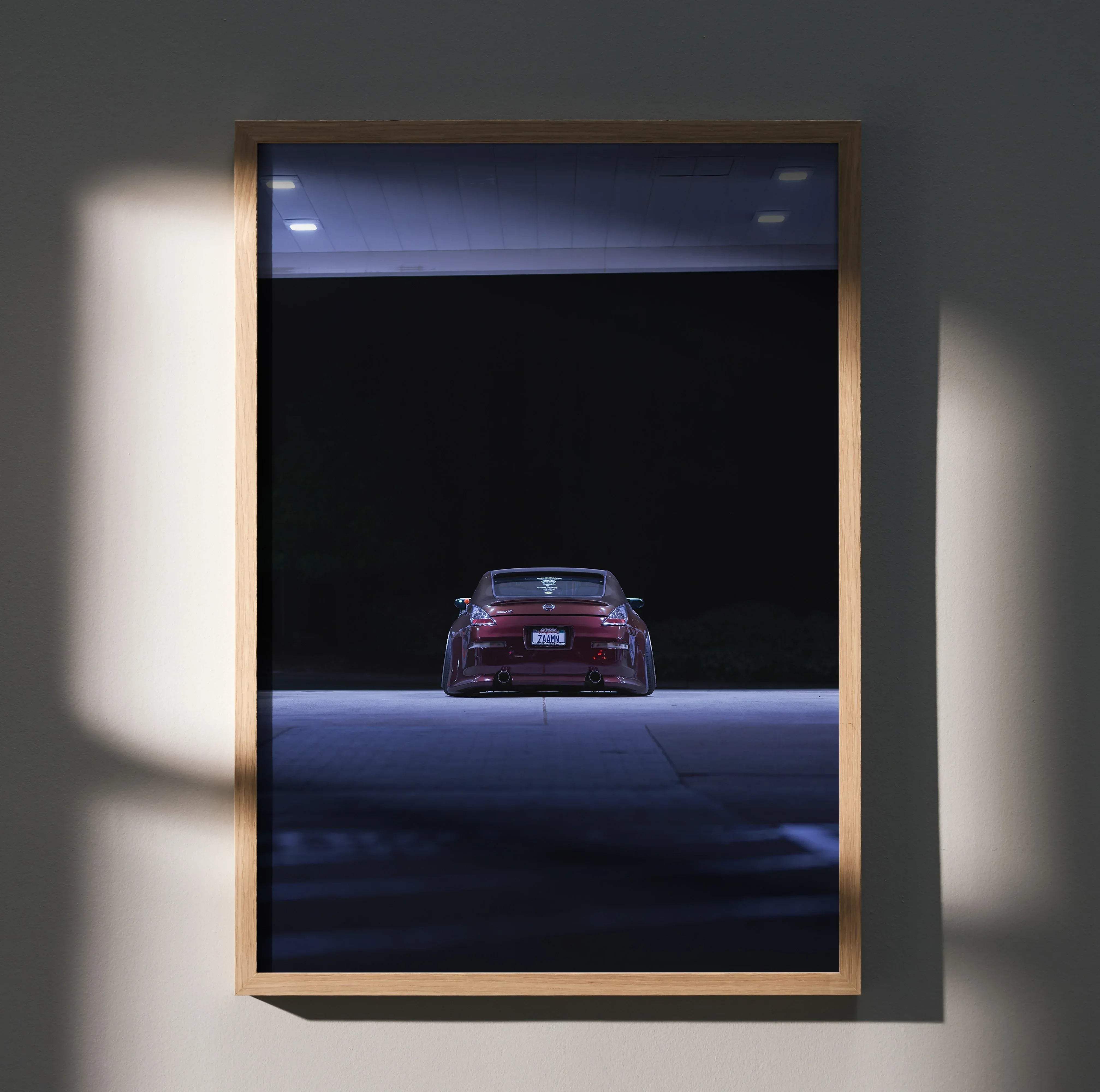 A framed high resolution automotive art poster showing the back of a red Nissan 350Z sports car in low light