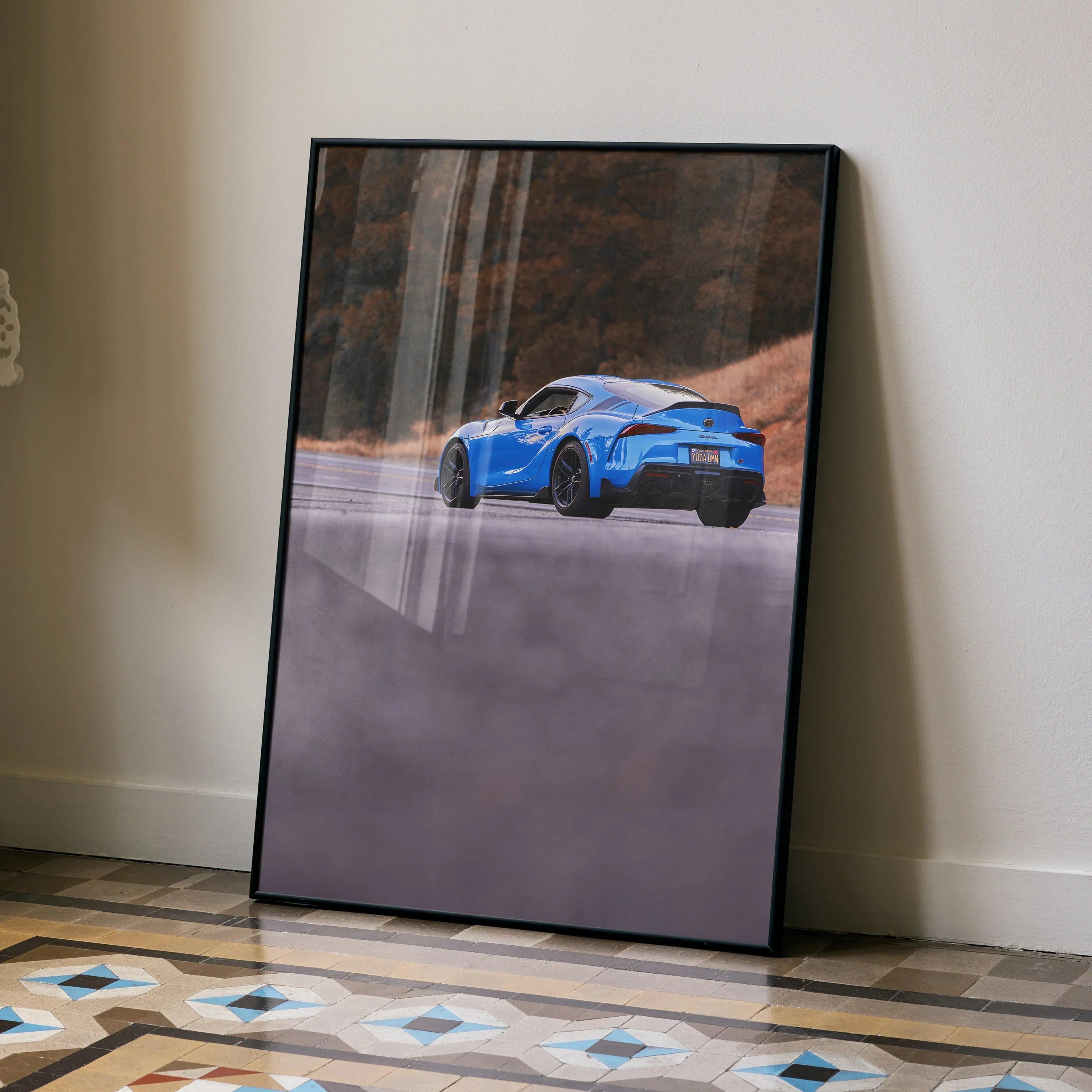 Toyota Supra MK5 in blue on a scenic road poster with black frame, automotive wall art.