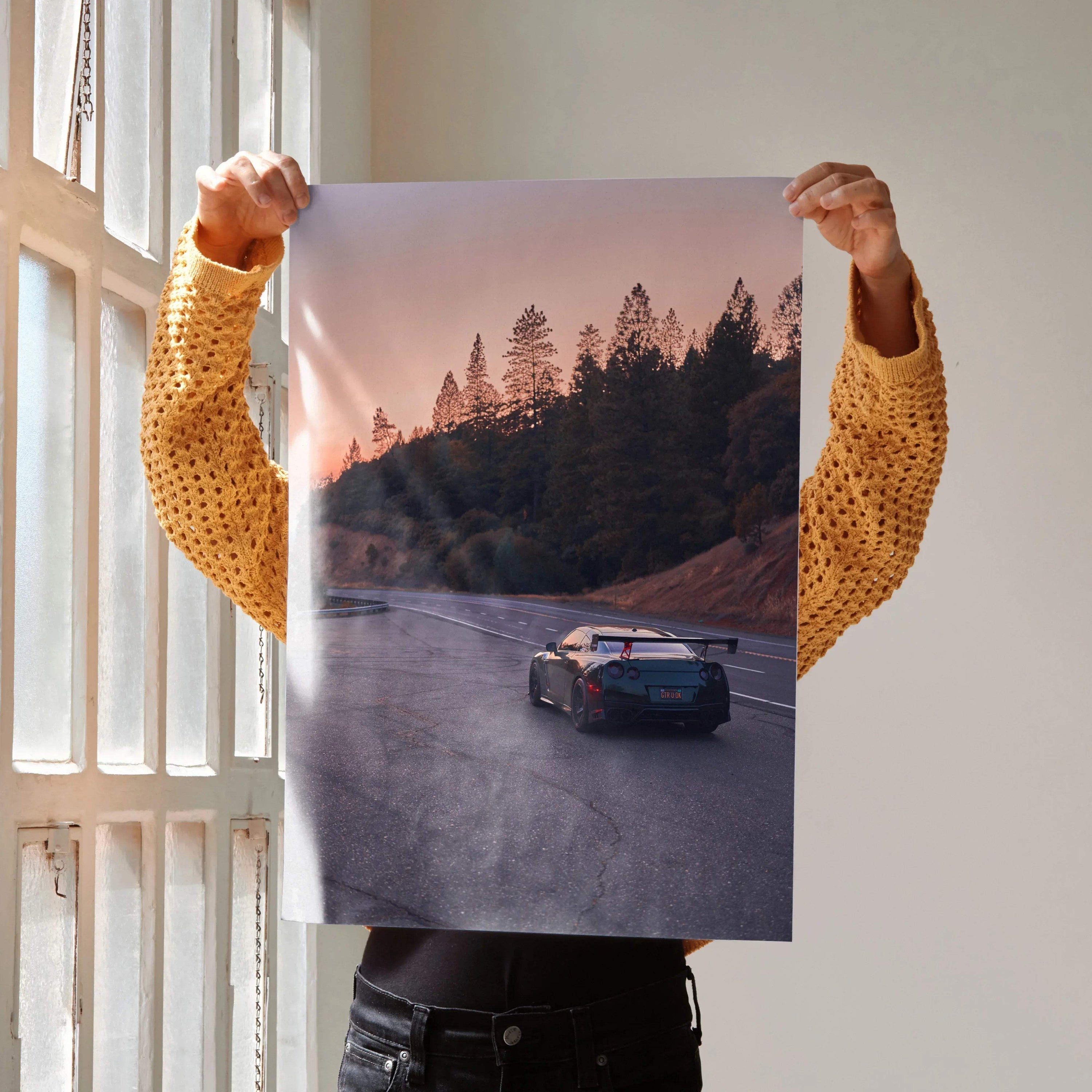 Nissan GTR R35 driving on scenic road at sunset poster wall art with forest background.