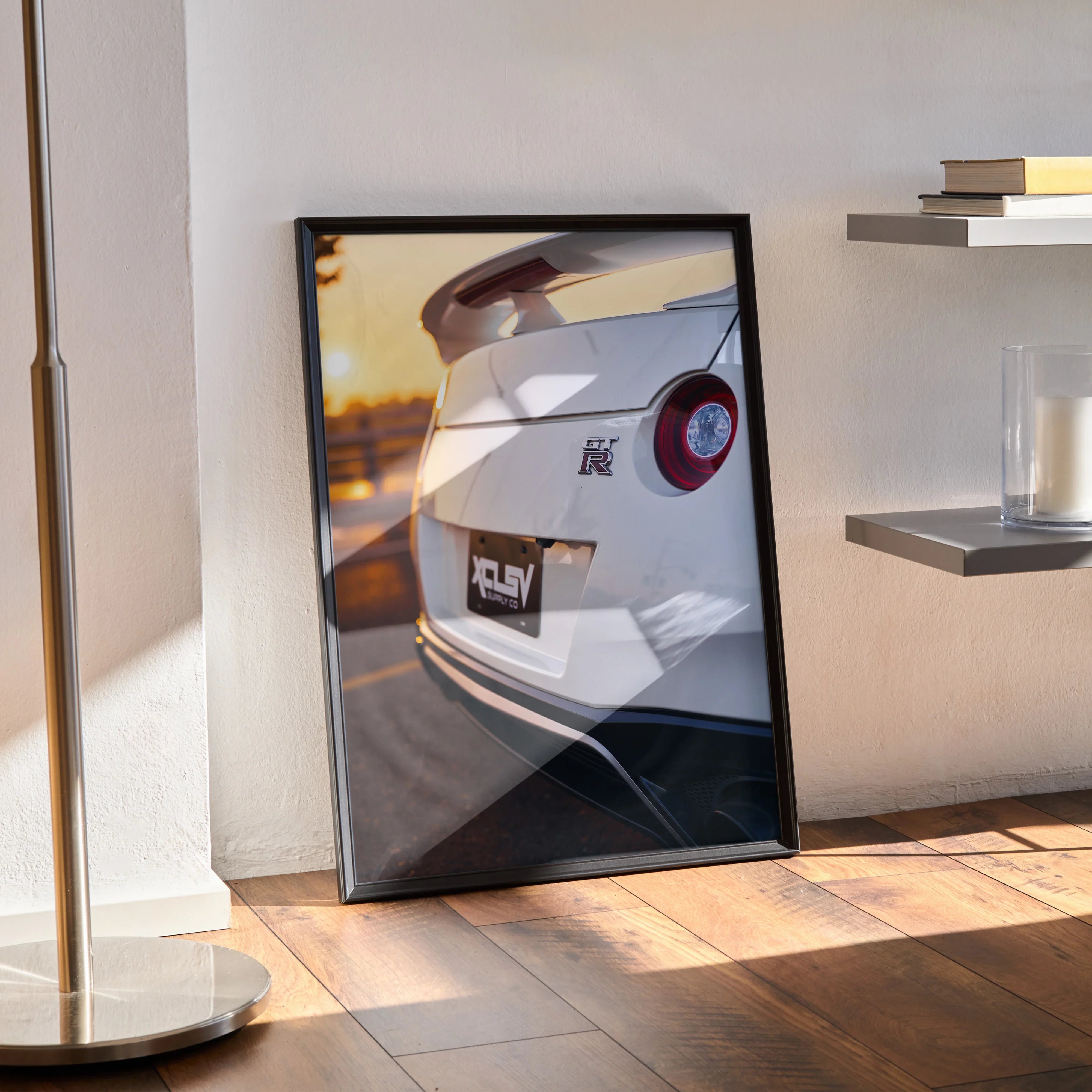 Framed Nissan GTR R35 rear view wall art poster with sunset lighting on hardwood floor.