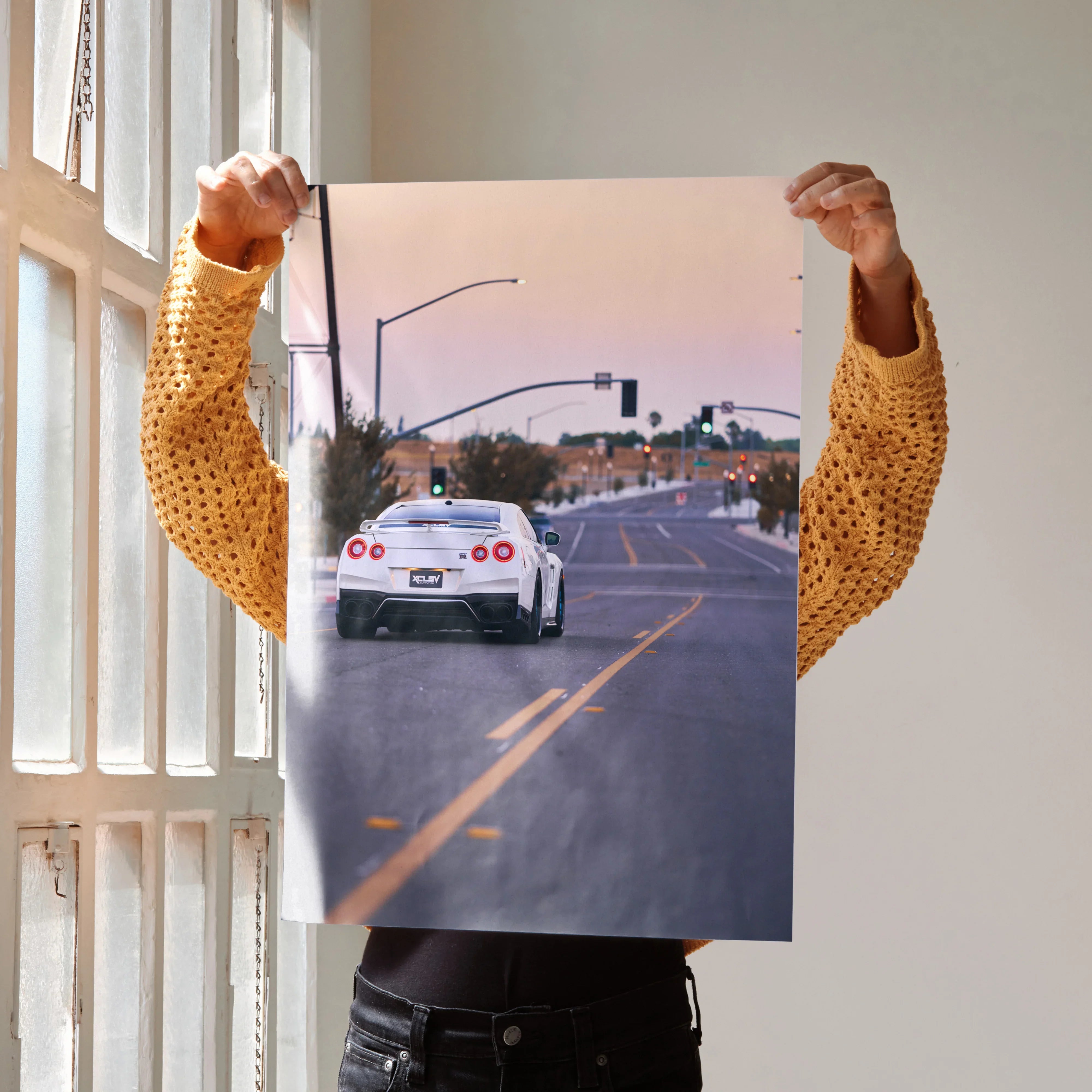 Nissan GTR R35 driving on city road poster wall art with sunset sky and traffic lights.