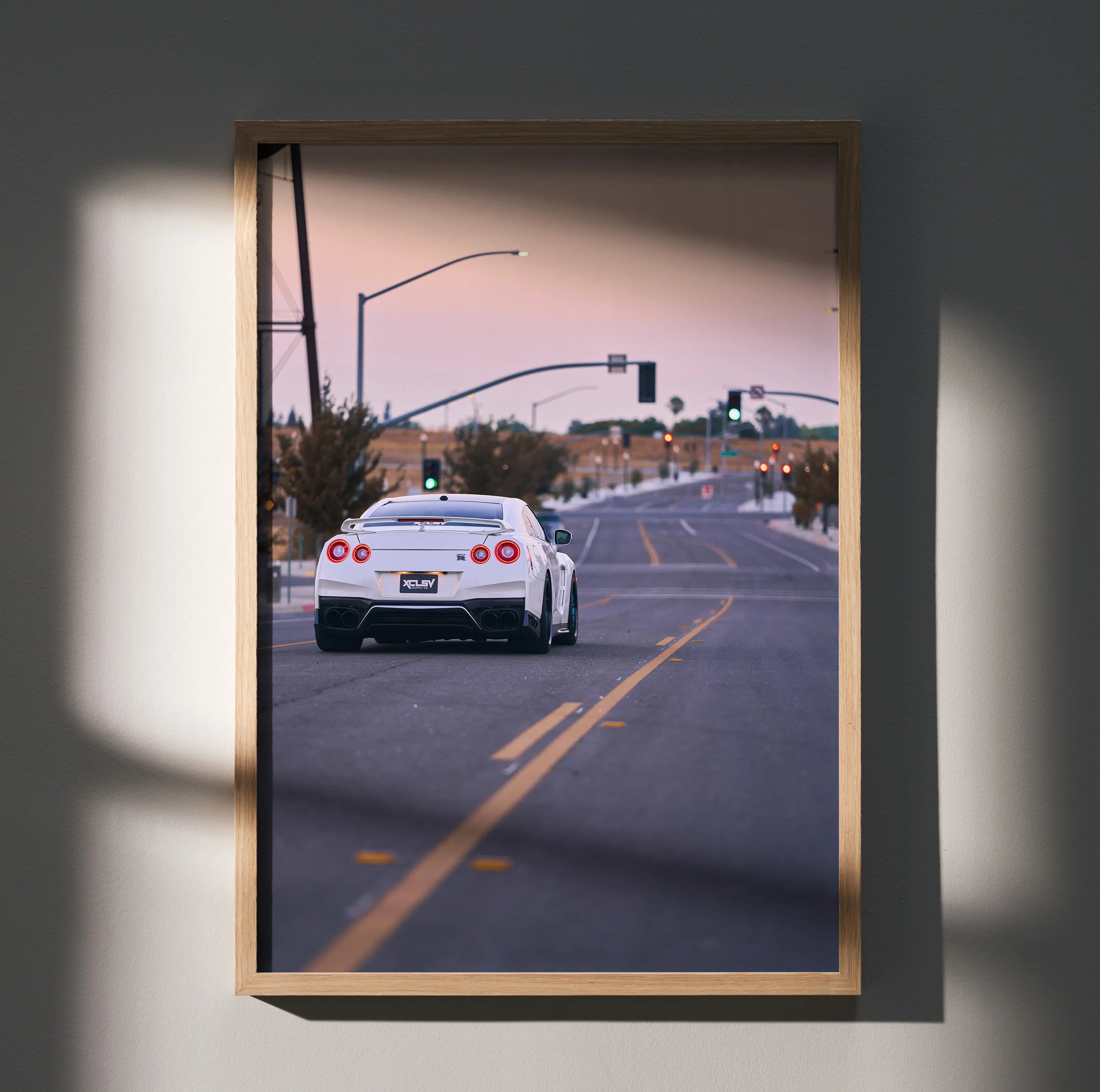Nissan GTR R35 driving on road at sunset poster wall art in wooden frame.