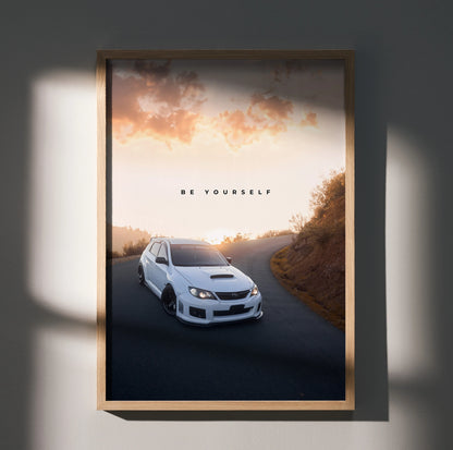 Subaru WRX STI poster wall art with "Be Yourself" text, white car on scenic road at sunset.