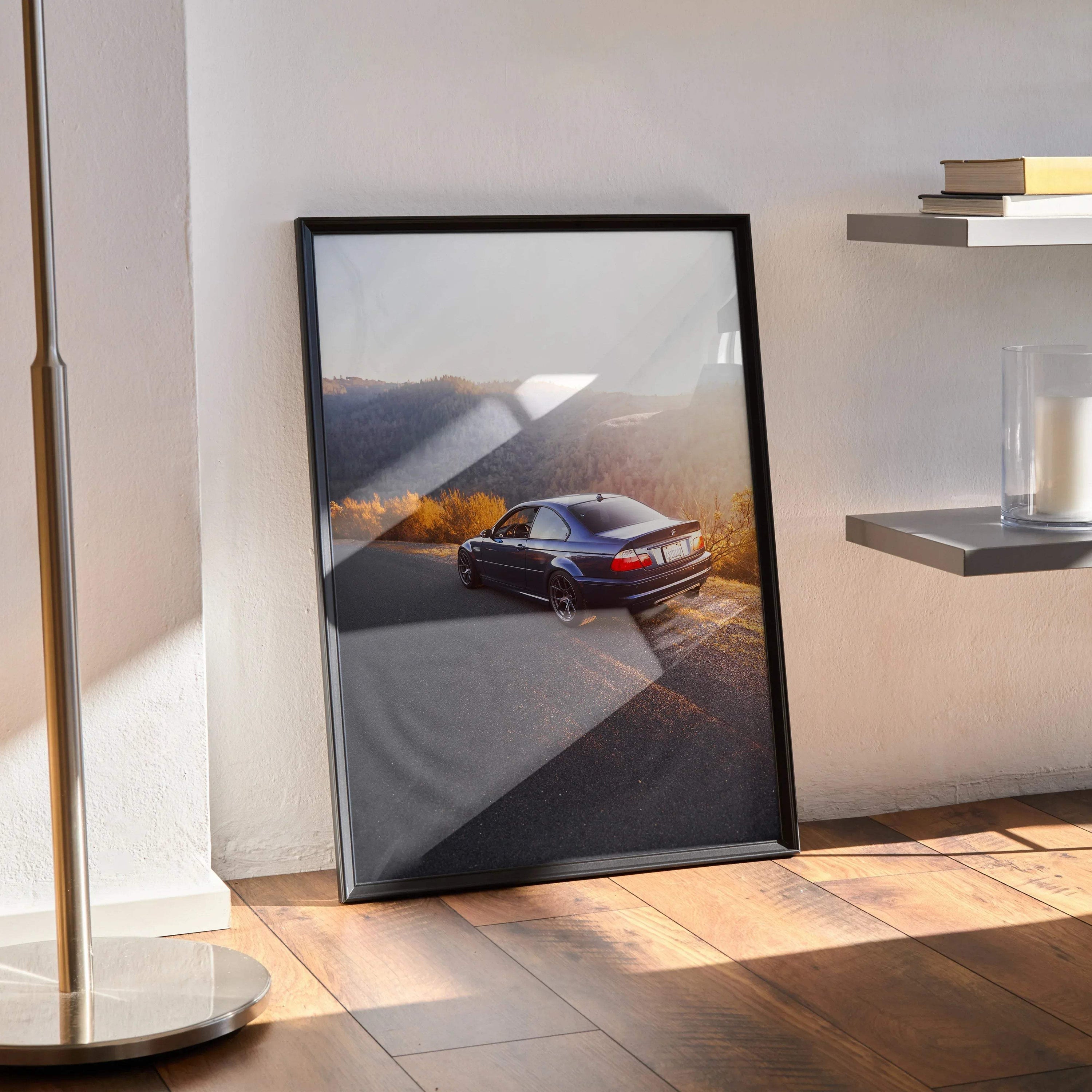 BMW E46 M3 poster wall art showcasing the car on a scenic mountain road in black frame.